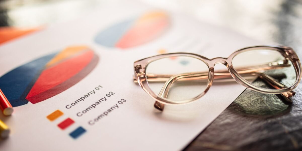 Close-up of eyeglasses on a table with colorful business charts.