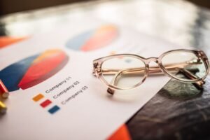 Close-up of eyeglasses on a table with colorful business charts.