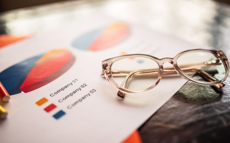 Close-up of eyeglasses on a table with colorful business charts.