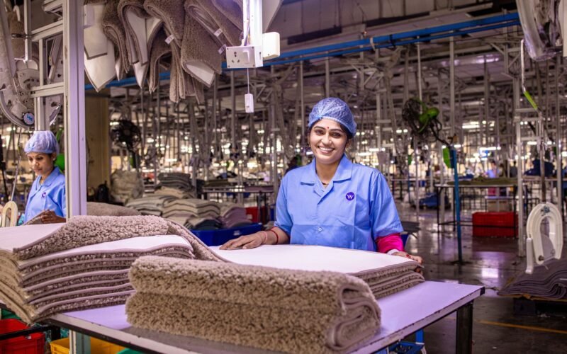 A smiling female worker in a textile factory, handling fabric with care.