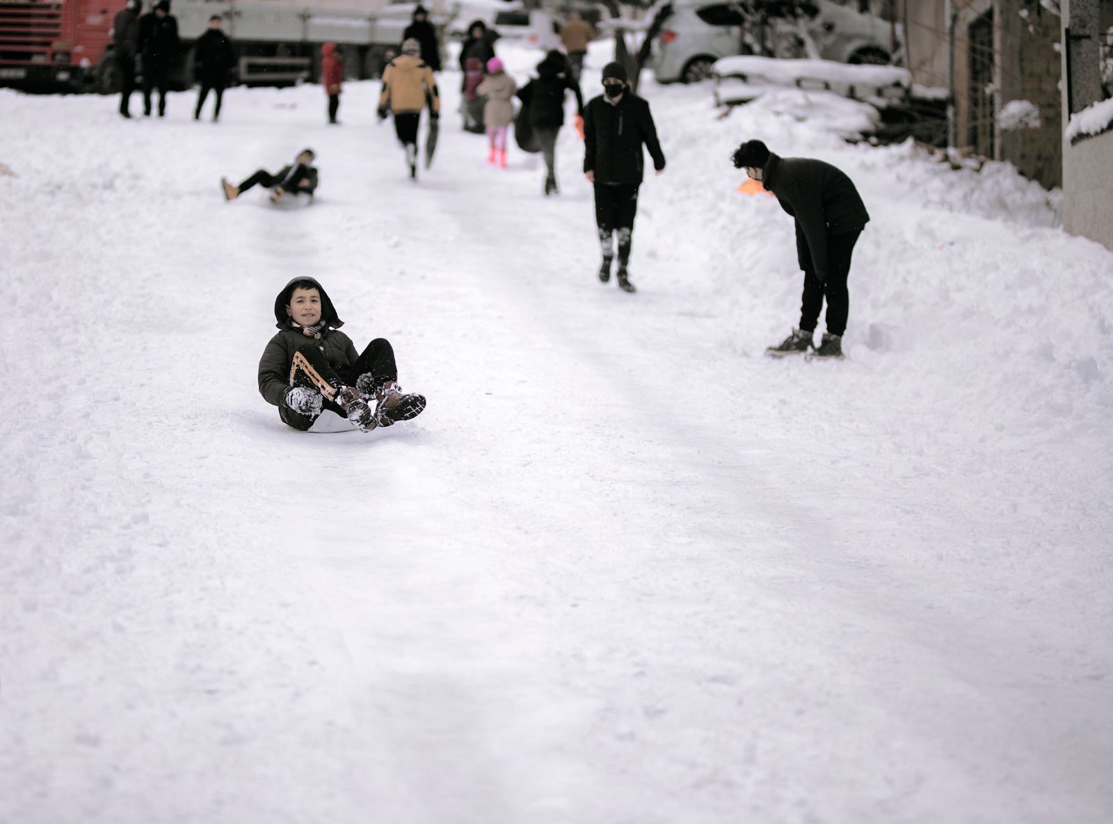 Kids enjoying sledding on a snowy street in Istanbul, Turkey. Winter fun and leisure activity.
